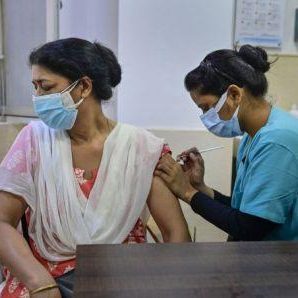 A health worker gives a booster dose against COVID-19 to a woman at a private hospital in New Delhi.